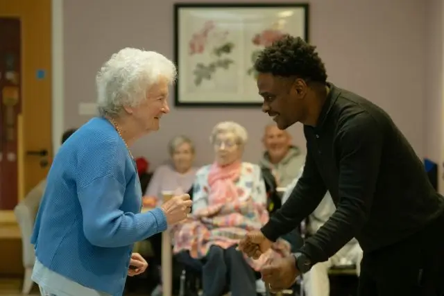 Caregiver sitting with an elderly resident in a warm home setting